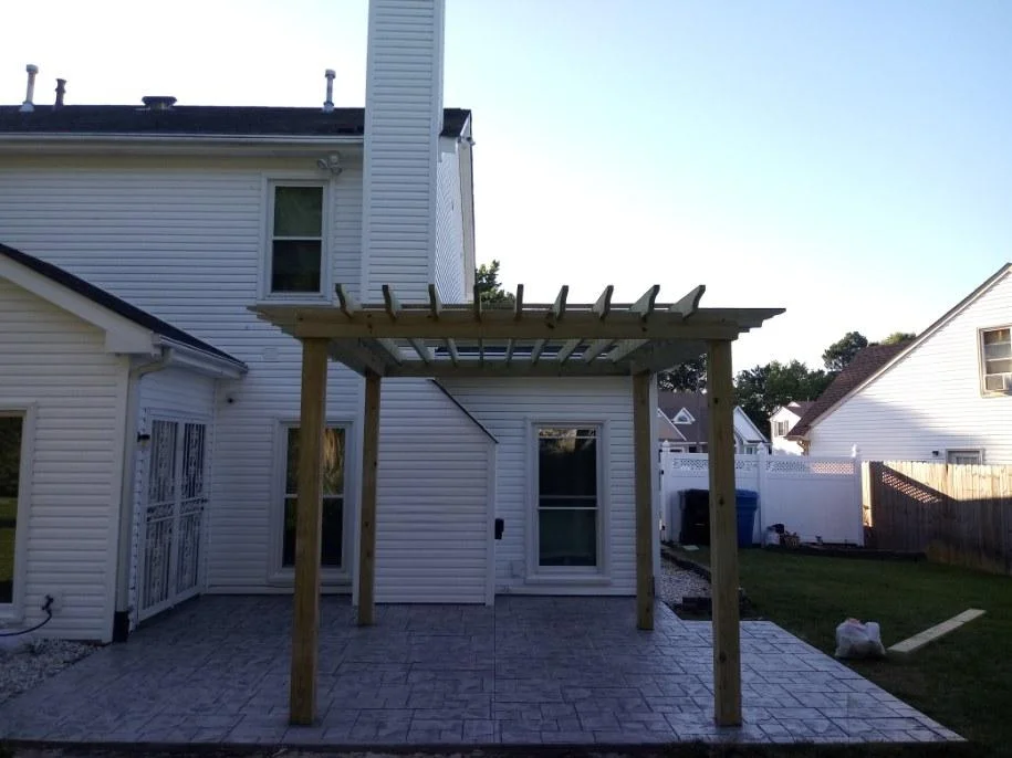 Finished custom pergola over a stamped concrete patio behind a Chesapeake home